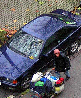 bag woman next to blue sedan